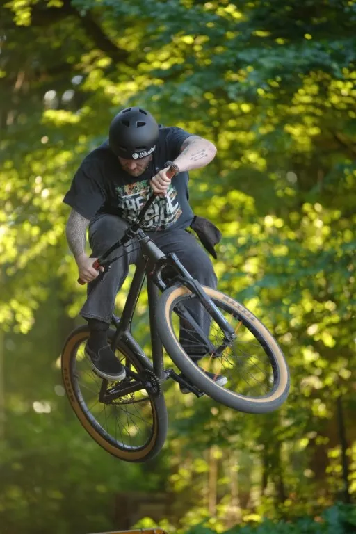 Biker springt im sommerlichen Grün