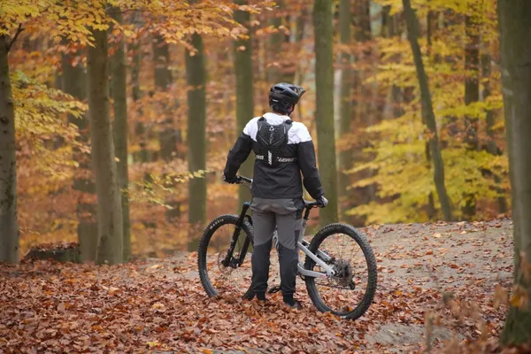 Mountainbiker steht im herbstlichen Wald