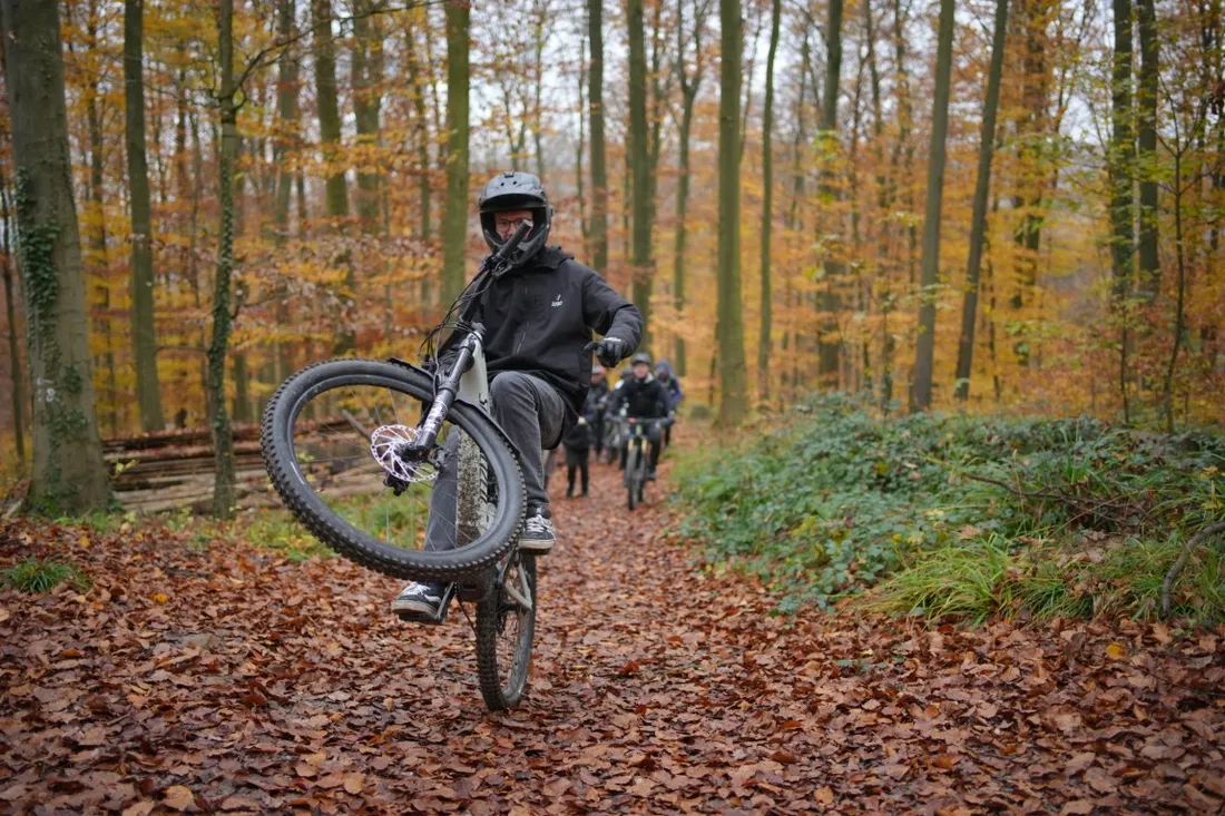 Biker fährt einen Wheelie im Herbstlaub